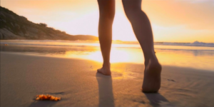 Barefoot womans legs, as she walks on the beach